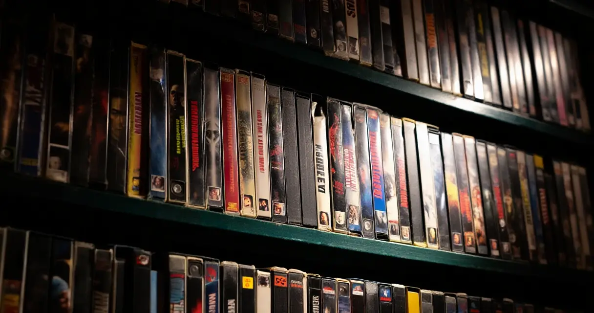 Vanha videovuokraamon hylly täynnä VHS-kasetteja, kauhuelokuvan tunnelma